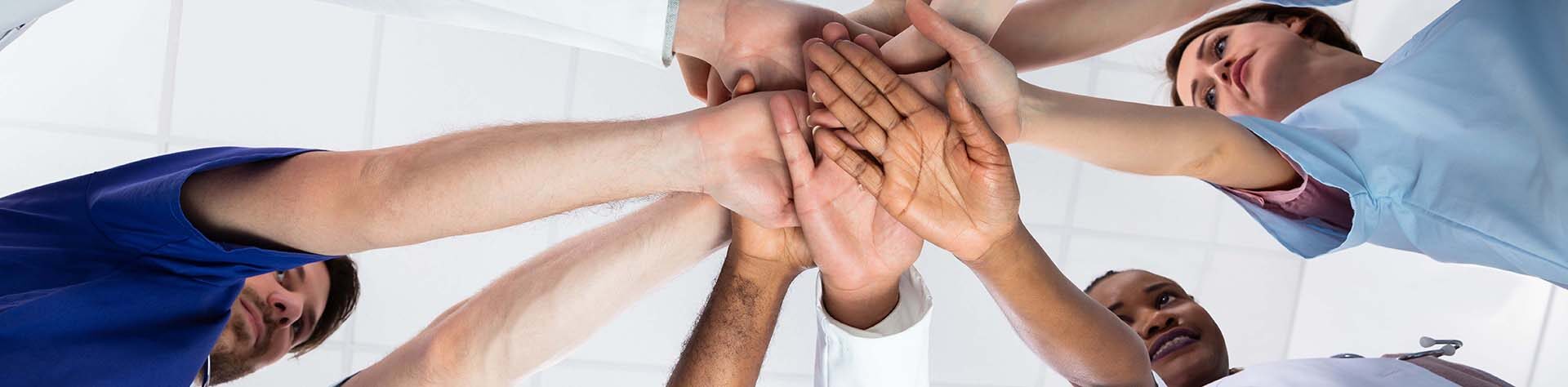 Low,Angle,View,Of,Doctor,Stacking,Hands,Together,In,Hospital