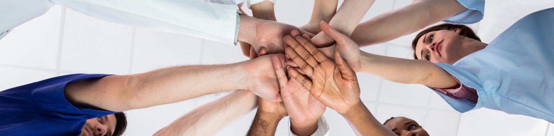 Low,Angle,View,Of,Doctor,Stacking,Hands,Together,In,Hospital
